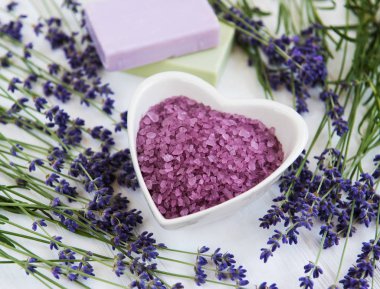 Deniz tuzu, sabun ve taze lavanta çiçekleri beyaz bir arka plan üzerinde kalp şeklinde bir kase