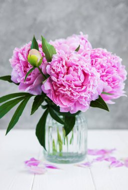 Beyaz ahşap bir masa üzerinde pembe şakayık çiçekli vazo