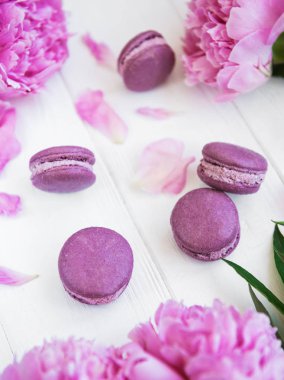 Beyaz ahşap bir masa üzerinde macarons ile pembe şakayık