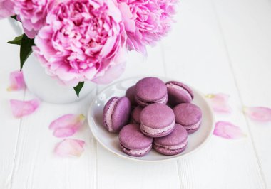 Beyaz ahşap bir masa üzerinde macarons ile pembe şakayık