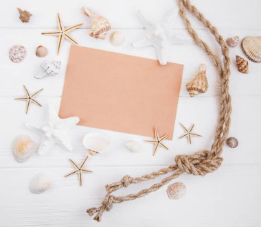 Holiday beach konseptiyle kabukları, seastars ve Beyaz ahşap zemin üzerinde boş bir kartpostal