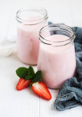 Kavanoz bir beyaz tahta masada çilekli yoğurt ile