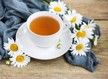 Eski ahşap bir masa üzerinde papatya çiçeği ile bitkisel çay