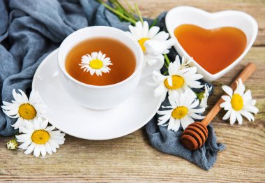 Eski ahşap bir masa üzerinde papatya çiçeği ile bitkisel çay