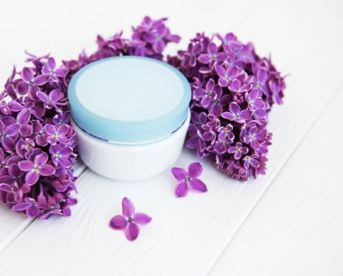 Eflatun çiçekler ve kozmetik krem beyaz ahşap zemin üzerinde
