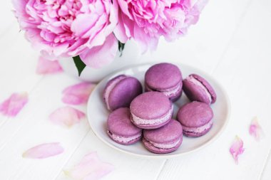 Beyaz ahşap bir masa üzerinde macarons ile pembe şakayık