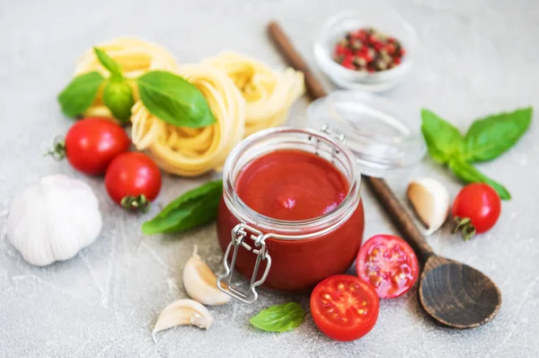 Jar with tomato sauce and ingredients on a stone background