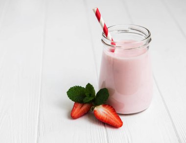 Beyaz ahşap bir masa üzerinde çilekli yoğurt ile jar