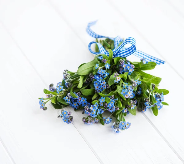 Forget-me-nots flowers with ribbon on a wooden background