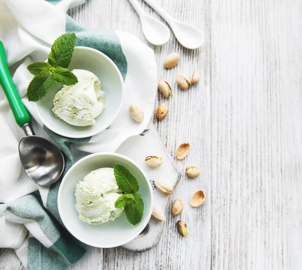 pistachio ice cream and mint with pistachio nuts on a old wooden background