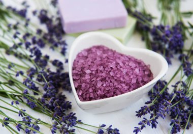 Deniz tuzu, sabun ve taze lavanta çiçekleri beyaz bir arka plan üzerinde kalp şeklinde bir kase