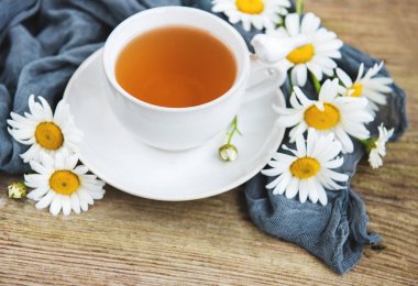 Eski ahşap bir masa üzerinde papatya çiçeği ile bitkisel çay