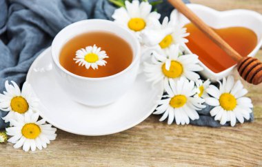 Eski ahşap bir masa üzerinde papatya çiçeği ile bitkisel çay