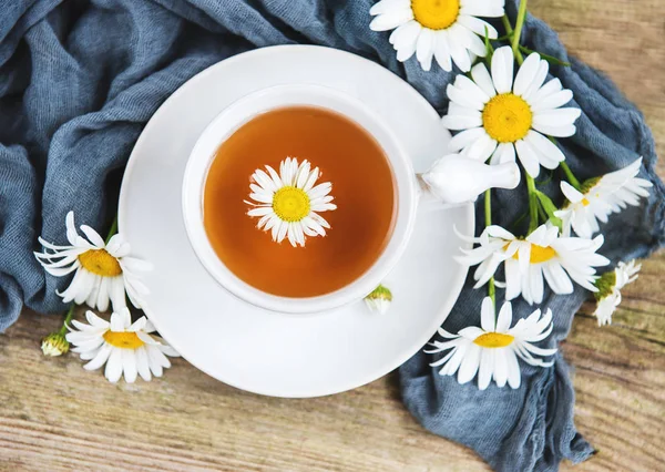 Eski ahşap bir masa üzerinde papatya çiçeği ile bitkisel çay