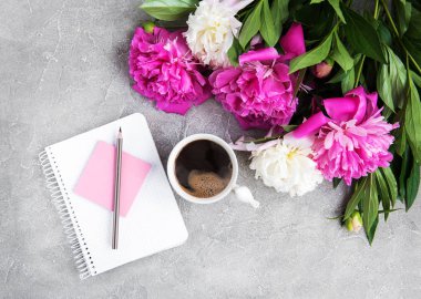 Eski bir taş zemin üzerine peonies ve kahve ile not defteri