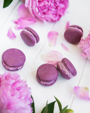Beyaz ahşap bir masa üzerinde macarons ile pembe şakayık