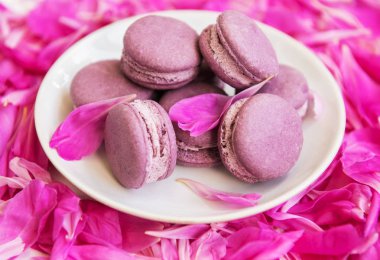 Beyaz ahşap bir masa üzerinde macarons ile pembe şakayık yaprakları