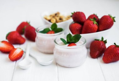 Sağlıklı Kahvaltı, yoğurt, taze çilek ve granola Beyaz ahşap bir masa üzerinde