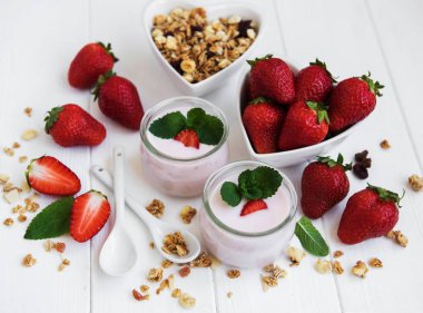 Sağlıklı Kahvaltı, yoğurt, taze çilek ve granola Beyaz ahşap bir masa üzerinde