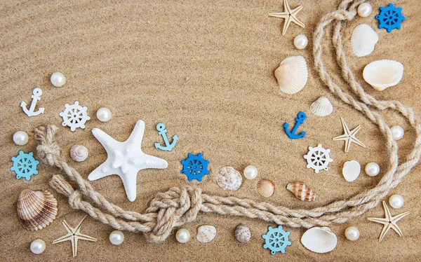 Seashells and sea decorations with rope on a sand background