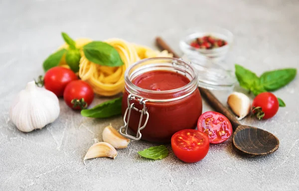 Jar with tomato sauce and ingredients on a stone background
