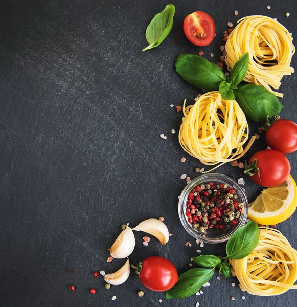 İtalyan gıda maddeleri. Makarna, domates, fesleğen ve siyah bir zemin üzerine baharat