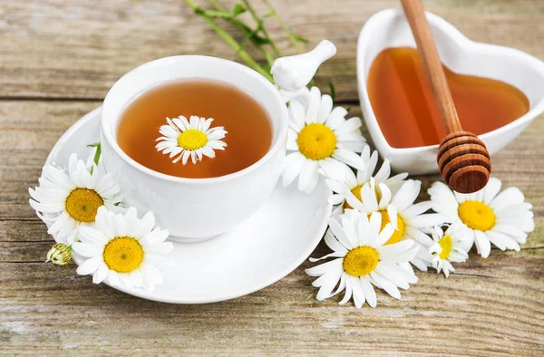 Eski ahşap bir masa üzerinde papatya çiçeği ile bitkisel çay