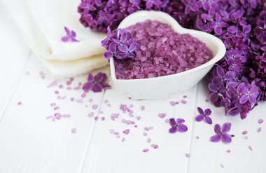 Spa havlu ve beyaz ahşap zemin üzerinde eflatun çiçekler ürünlerle Masaj