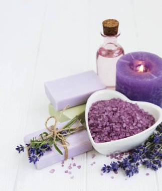 Deniz tuzu, uçucu yağlar, sabun ve taze lavanta çiçekleri ahşap arka plan üzerinde kalp şeklinde bir kase