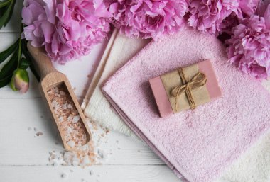 kalıp el yapımı sabun, yumuşak havlu ve bir beyaz tahta masaya peony çiçek