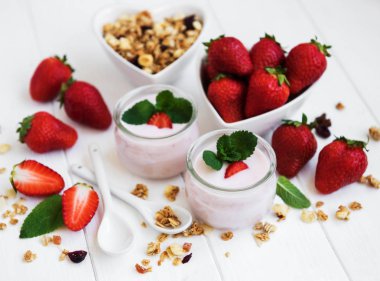 Sağlıklı Kahvaltı, yoğurt, taze çilek ve granola Beyaz ahşap bir masa üzerinde