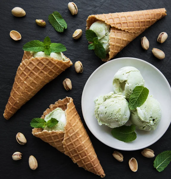 pistachio ice cream and mint with pistachio nuts on a black stone background