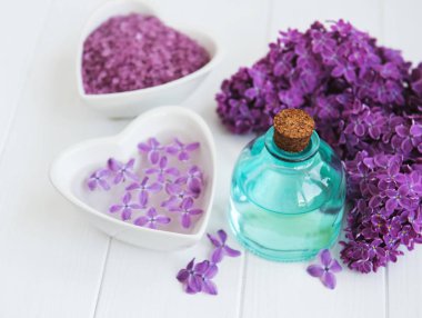 Esans ve deniz tuzu Beyaz ahşap zemin üzerinde eflatun çiçekli