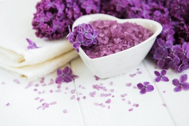 Spa havlu ve beyaz ahşap zemin üzerinde eflatun çiçekler ürünlerle Masaj