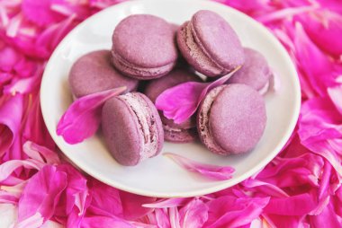 Beyaz ahşap bir masa üzerinde macarons ile pembe şakayık yaprakları