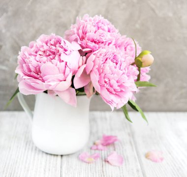 Beyaz ahşap bir masa üzerinde pembe şakayık çiçekli vazo