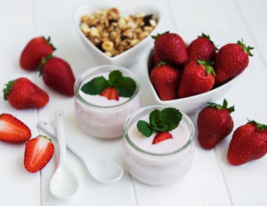 Sağlıklı Kahvaltı, yoğurt, taze çilek ve granola Beyaz ahşap bir masa üzerinde