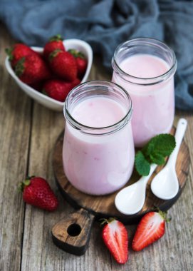 Kavanoz eski ahşap bir masa üzerinde çilekli yoğurt ile