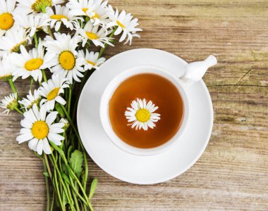 Eski ahşap bir masa üzerinde papatya çiçeği ile bitkisel çay