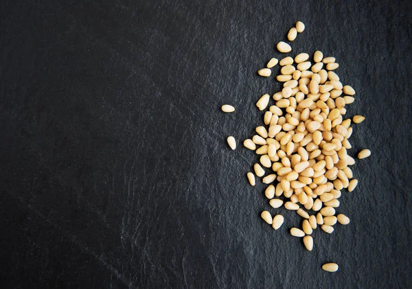 Pine nuts on a black stone background