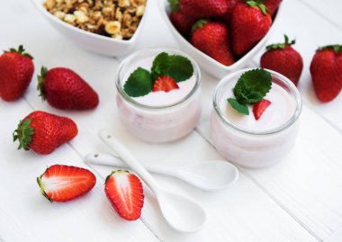 Sağlıklı Kahvaltı, yoğurt, taze çilek ve granola Beyaz ahşap bir masa üzerinde