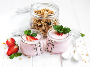 Sağlıklı Kahvaltı, yoğurt, taze çilek ve granola Beyaz ahşap bir masa üzerinde