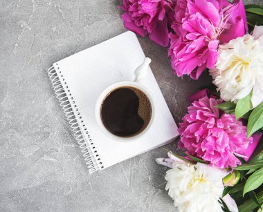 Eski bir taş zemin üzerine peonies ve kahve ile not defteri