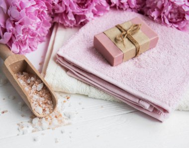 kalıp el yapımı sabun, yumuşak havlu ve bir beyaz tahta masaya peony çiçek