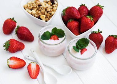 Sağlıklı Kahvaltı, yoğurt, taze çilek ve granola Beyaz ahşap bir masa üzerinde