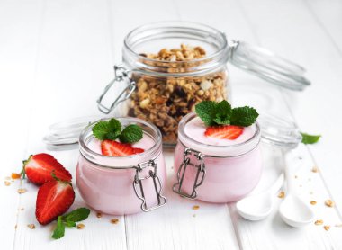 Sağlıklı Kahvaltı, yoğurt, taze çilek ve granola Beyaz ahşap bir masa üzerinde