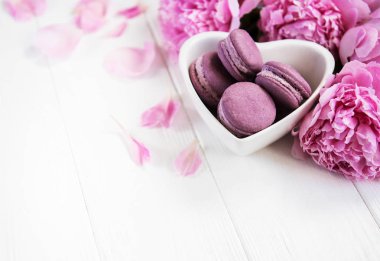 Pembe şakayık çiçekleri Beyaz ahşap bir masa üzerinde macarons ile