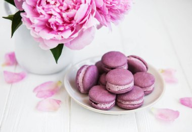 Beyaz ahşap bir masa üzerinde macarons ile pembe şakayık