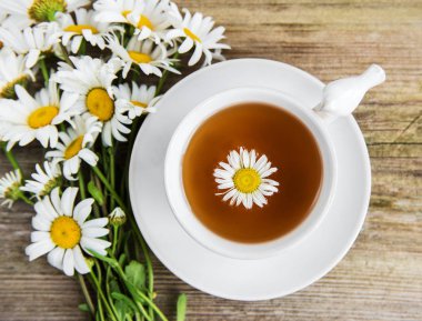 Eski ahşap bir masa üzerinde papatya çiçeği ile bitkisel çay