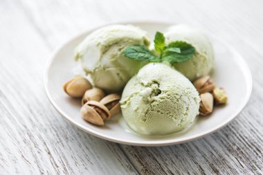 pistachio ice cream and mint with pistachio nuts on a old wooden background clipart